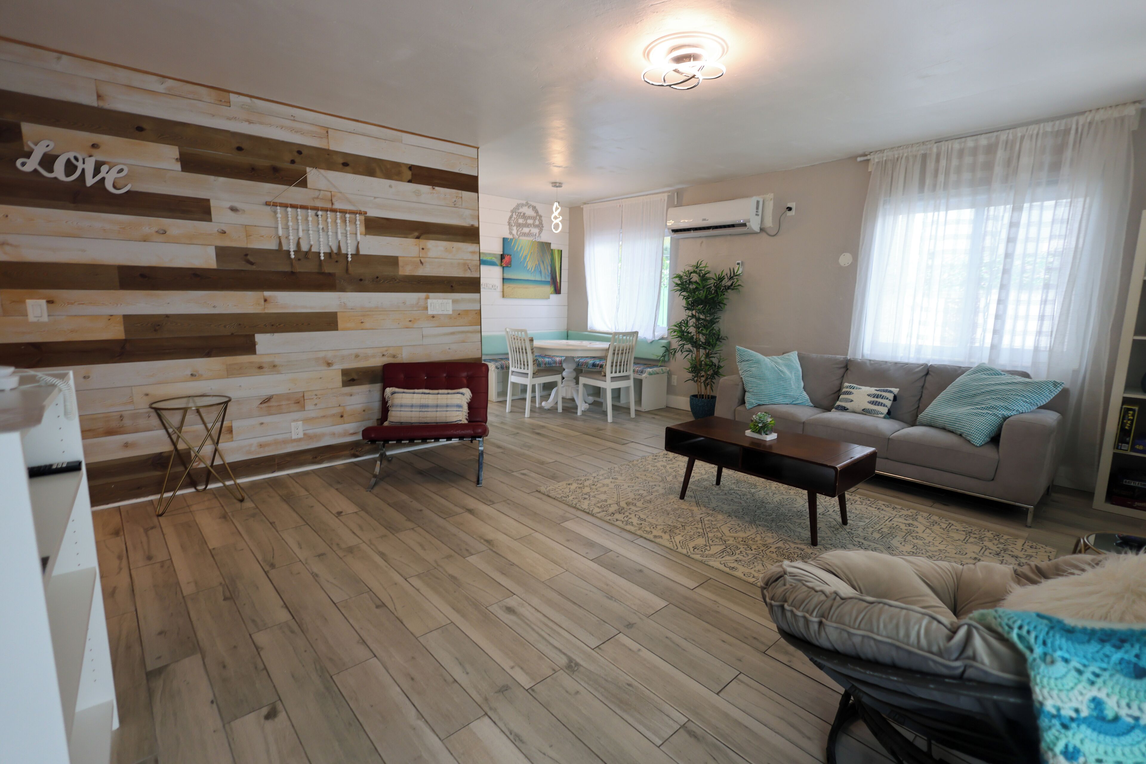 Een woonkamer met een houten wand, een rode stoel, een bank en een salontafel.