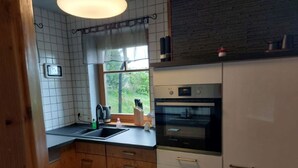 Una cocina con armarios de madera, horno empotrado y ventana con vista a follaje.