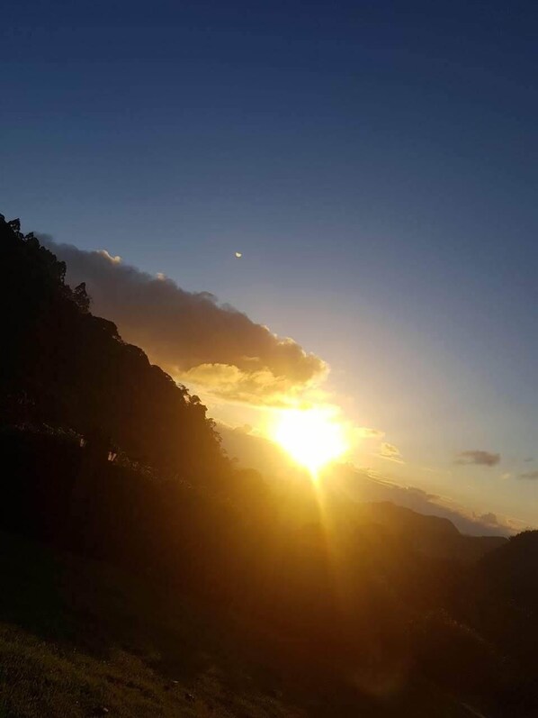 A sunset over a mountainous landscape with a clear sky.