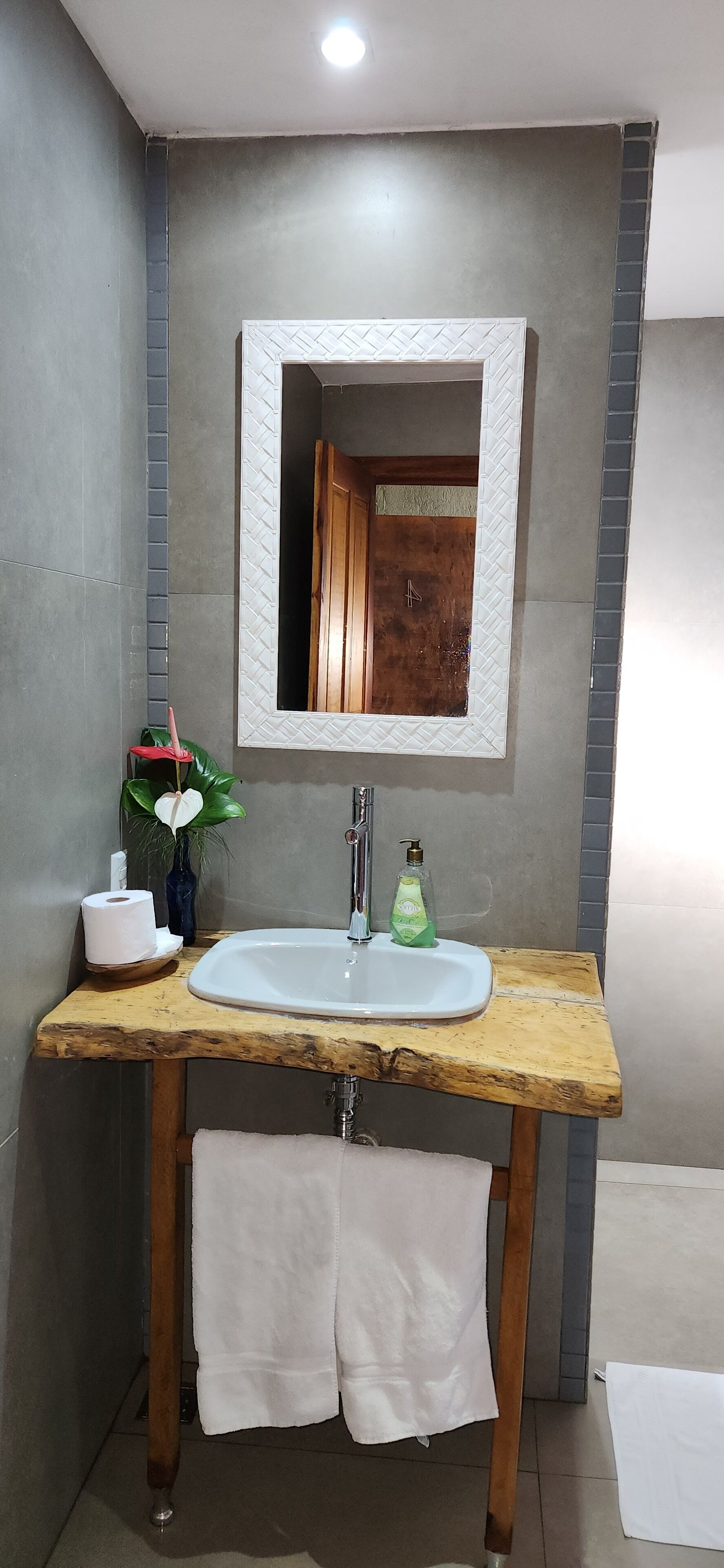 Une salle de bain avec un meuble-lavabo en bois, un lavabo blanc et un miroir.