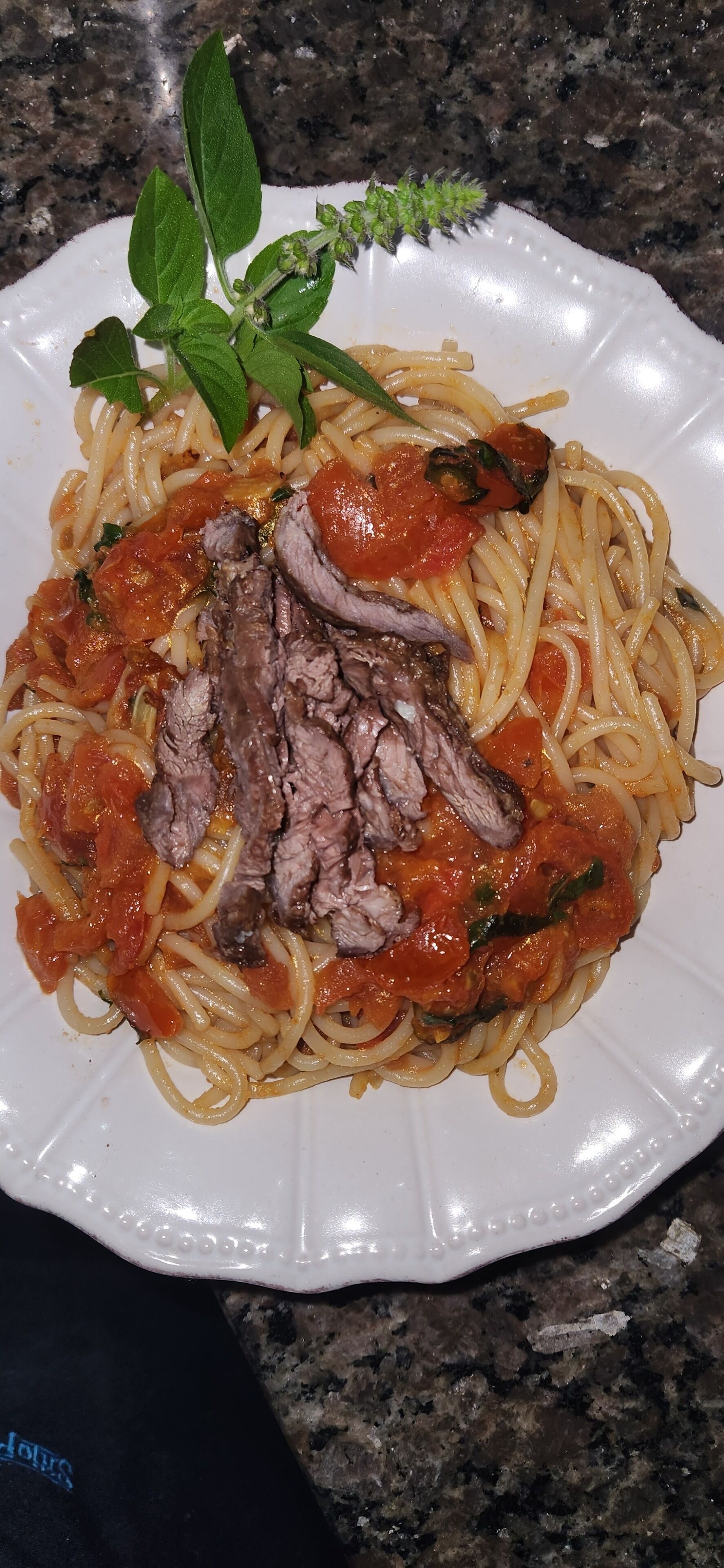 A plate of spaghetti with meat and tomato sauce, garnished with basil.