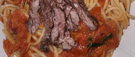 Un plato de espagueti con carne y salsa de tomate, adornado con albahaca.