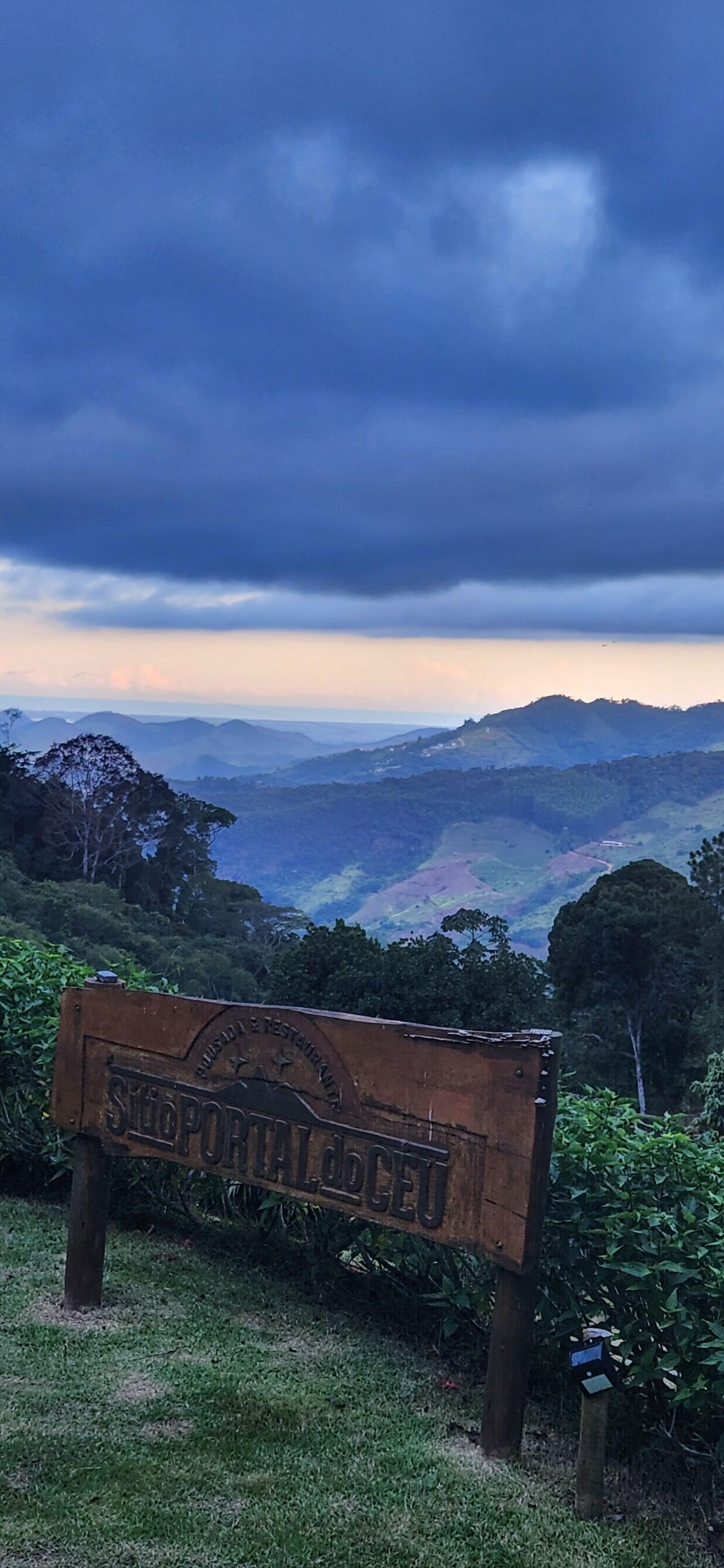 A wooden sign with the text "SMP PORTAL DOCEGO" in a natural setting with a mountainous landscape in the background.