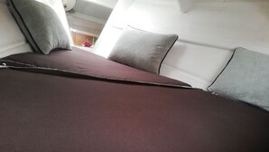 A bed with a dark brown mattress and pillows in shades of gray and brown. - Wild Escape Island Bay Experience (Sardegna)
