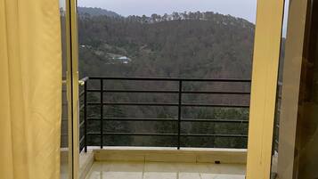 Enjoy a serene view of the forested hillside from this balcony with a glass door leading out to the outdoors.