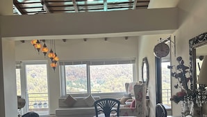 A dining area with a glass-top table, black chairs, and a decorative hanging light fixture.