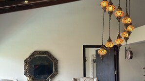 A room with floral-patterned armchairs, a wooden coffee table, a decorative mirror, and hanging lanterns.