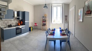 Una cocina moderna con armarios grises, un comedor con una mesa preparada para cuatro personas y un ventanal que proporciona luz natural.