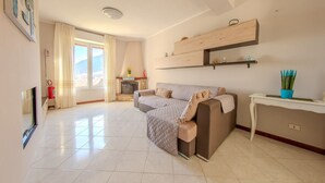 A spacious living room with a large sofa, a fireplace, and a dining area with a table and chairs. - Villa Maddalena - Scala (Scala)