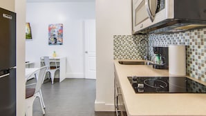 Une cuisine moderne équipée d’un four à micro-ondes, d’une cuisinière et d’un évier. Un coin repas avec une table et des chaises est également disponible.