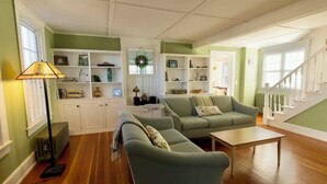 Un salon spacieux avec un canapé vert, une table basse et une bibliothèque remplie de livres et d’objets décoratifs.