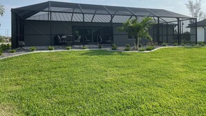 A modern building with a covered patio area, outdoor seating, and a well-maintained lawn. - Fun in the Sun!
Brand New Home! (Port Charlotte)