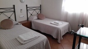 Een slaapkamer met twee bedden, elk voorzien van een hoofdeinde, nachtkastje en lamp.