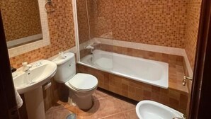 Een badkamer met douche, toilet, toiletbril en bad.