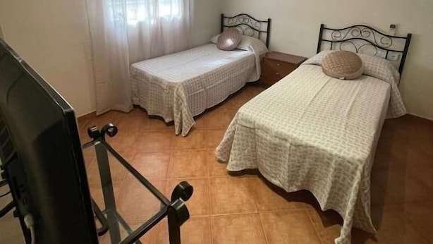 Een kleine, schone kamer met twee eenpersoonsbedden, een tafeltje en een stoel.