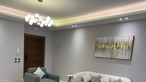 Un salon moderne avec un sol en marbre, des canapés gris et un lustre contemporain.