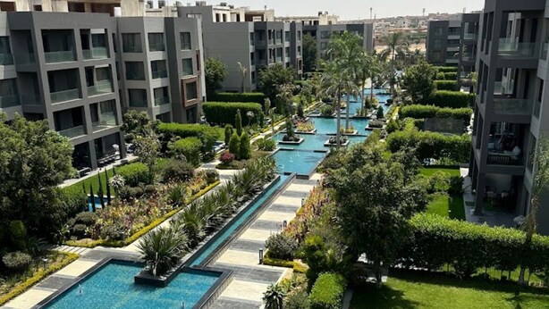 Un complexe résidentiel moderne doté de plusieurs piscines, de jardins bien entretenus et de bâtiments au design contemporain.