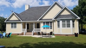 A single-story house with a front porch, a covered patio with outdoor furniture, and a garage.