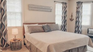 A neatly made bed with a headboard, a bedside table with a lamp, and a wall-mounted sign.