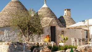 Un edificio de piedra con techos cónicos, un jarrón grande y mesas al aire libre.
