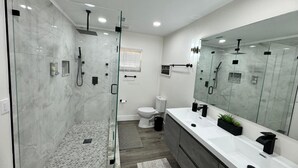 A modern bathroom with a glass-enclosed shower, a toilet, and a large mirror. - 4-Bed Bungalow close to Disney, Universal Studios and many fantastic restaurants (Orlando)