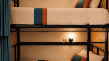 A bunk bed room with a wooden headboard, a wall-mounted light, and a power outlet.