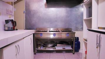 Una cocina con electrodomésticos de acero inoxidable, armarios blancos y una estufa a gas.