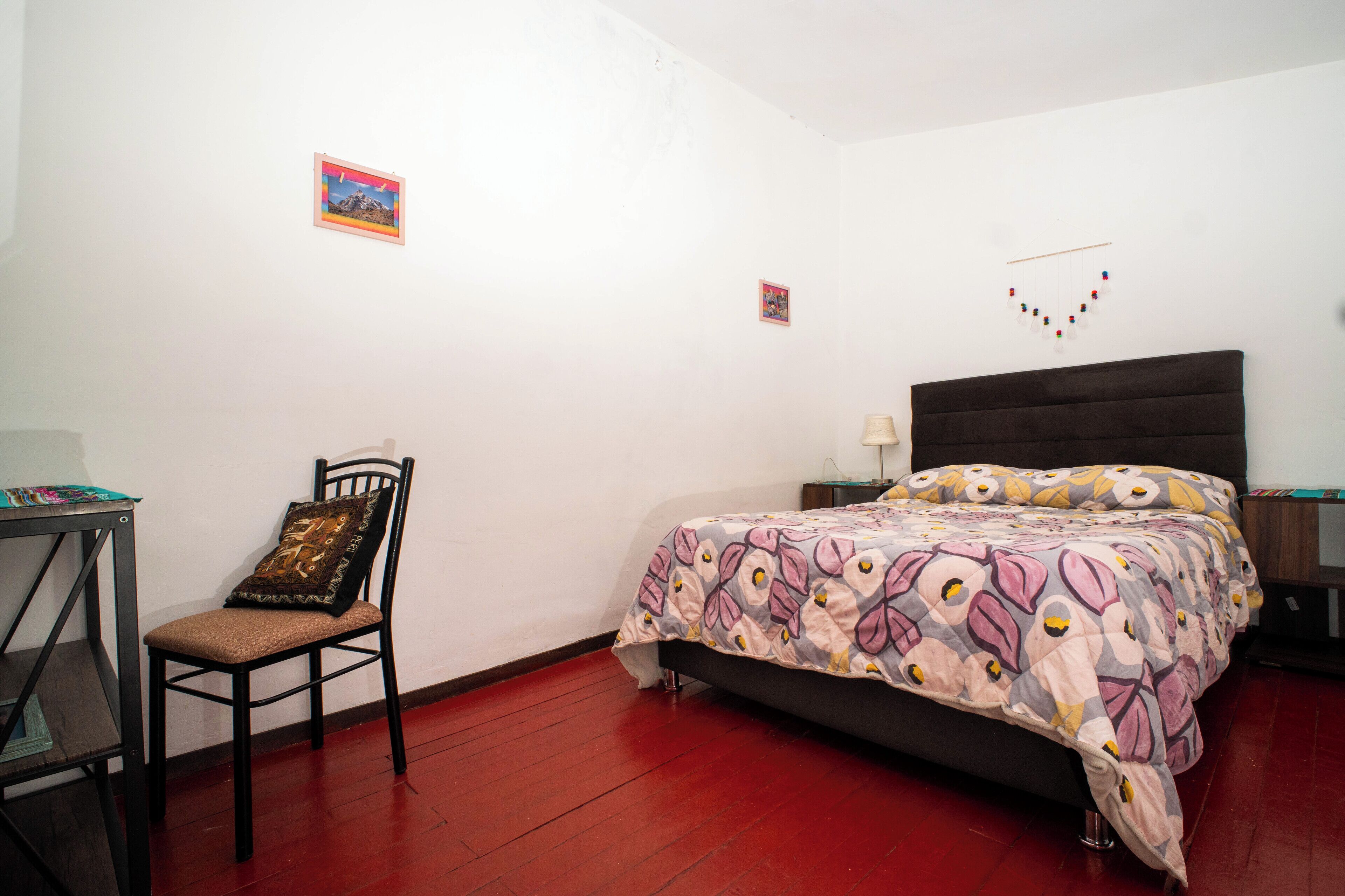 Un dormitorio con una cama, una silla, una mesita y dos adornos en la pared.