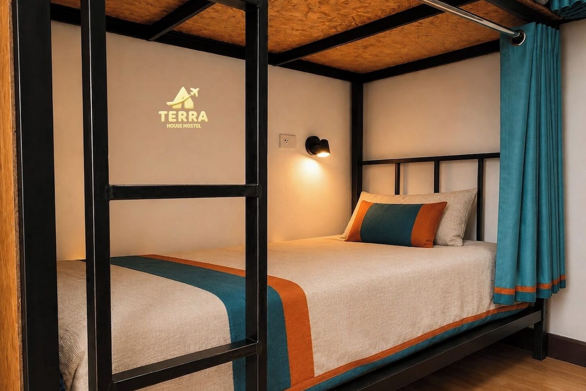 A bunk bed with a logo on the wall, a wall-mounted light, and a curtain.