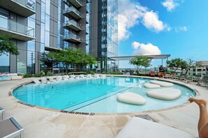 Relax by the pool surrounded by lounge chairs and a shaded pergola, with a clear view of the city.