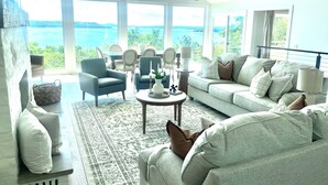 A spacious living room with a large window overlooking a scenic view, furnished with a sofa, armchairs, and a coffee table. - Fully remodeled lake house with gorgeous views of Bull Shoals Lake! (Lakeview)