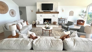 A modern living room with a fireplace, two sofas, a coffee table, and a television. - Fully remodeled lake house with gorgeous views of Bull Shoals Lake! (Lakeview)