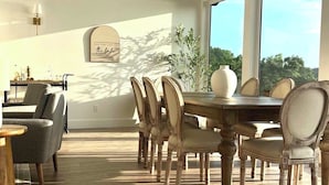 A dining area with a wooden table and chairs, a wall-mounted light, and a view of the outdoors. - Fully remodeled lake house with gorgeous views of Bull Shoals Lake! (Lakeview)