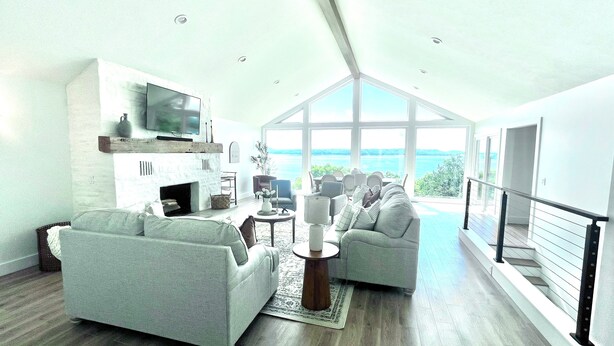 A spacious living room with a fireplace, comfortable seating, and a large window overlooking a scenic view. - Fully remodeled lake house with gorgeous views of Bull Shoals Lake! (Lakeview)