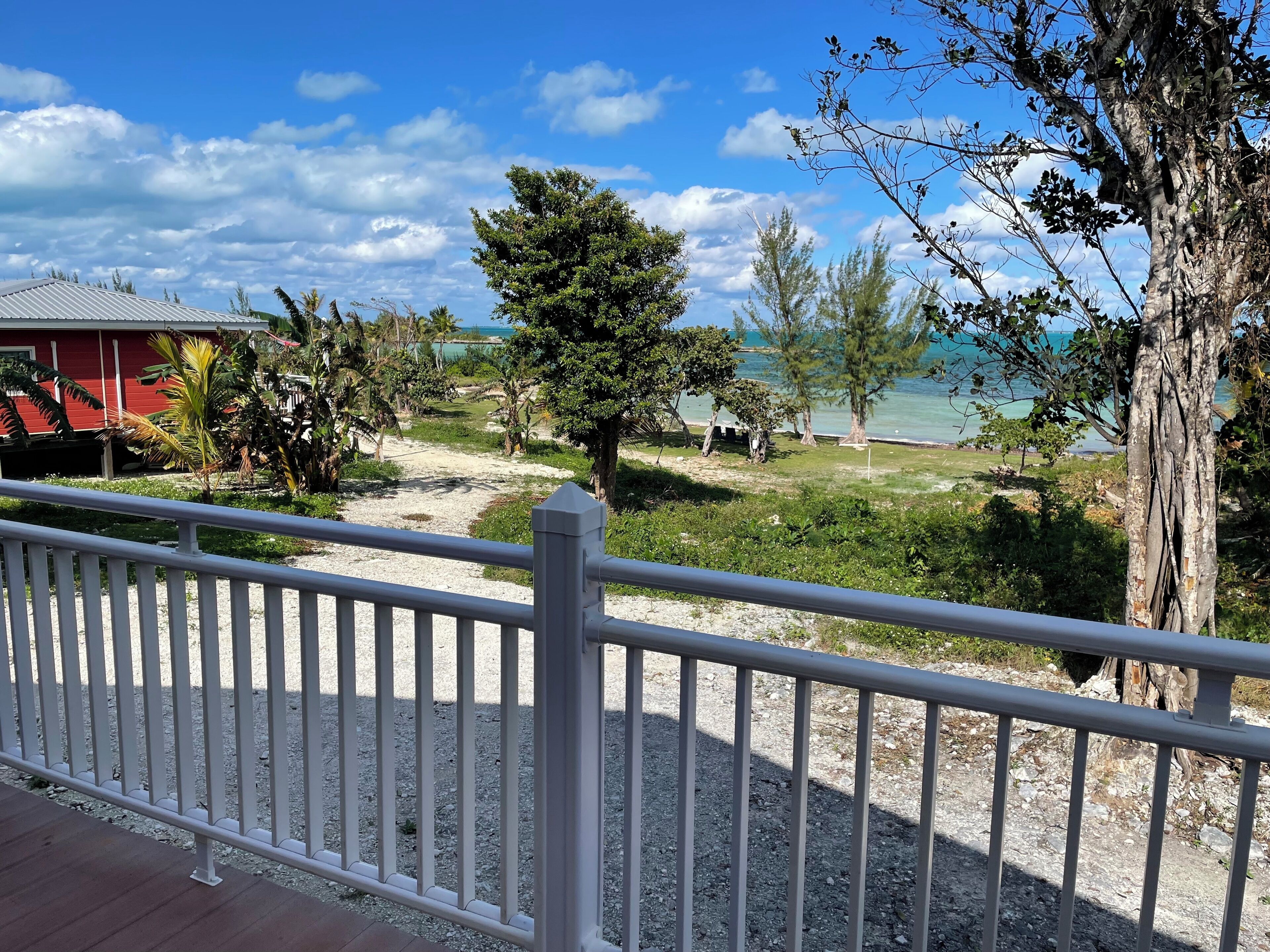 A coastal view with a white fence, a red building, and a beach in the background.