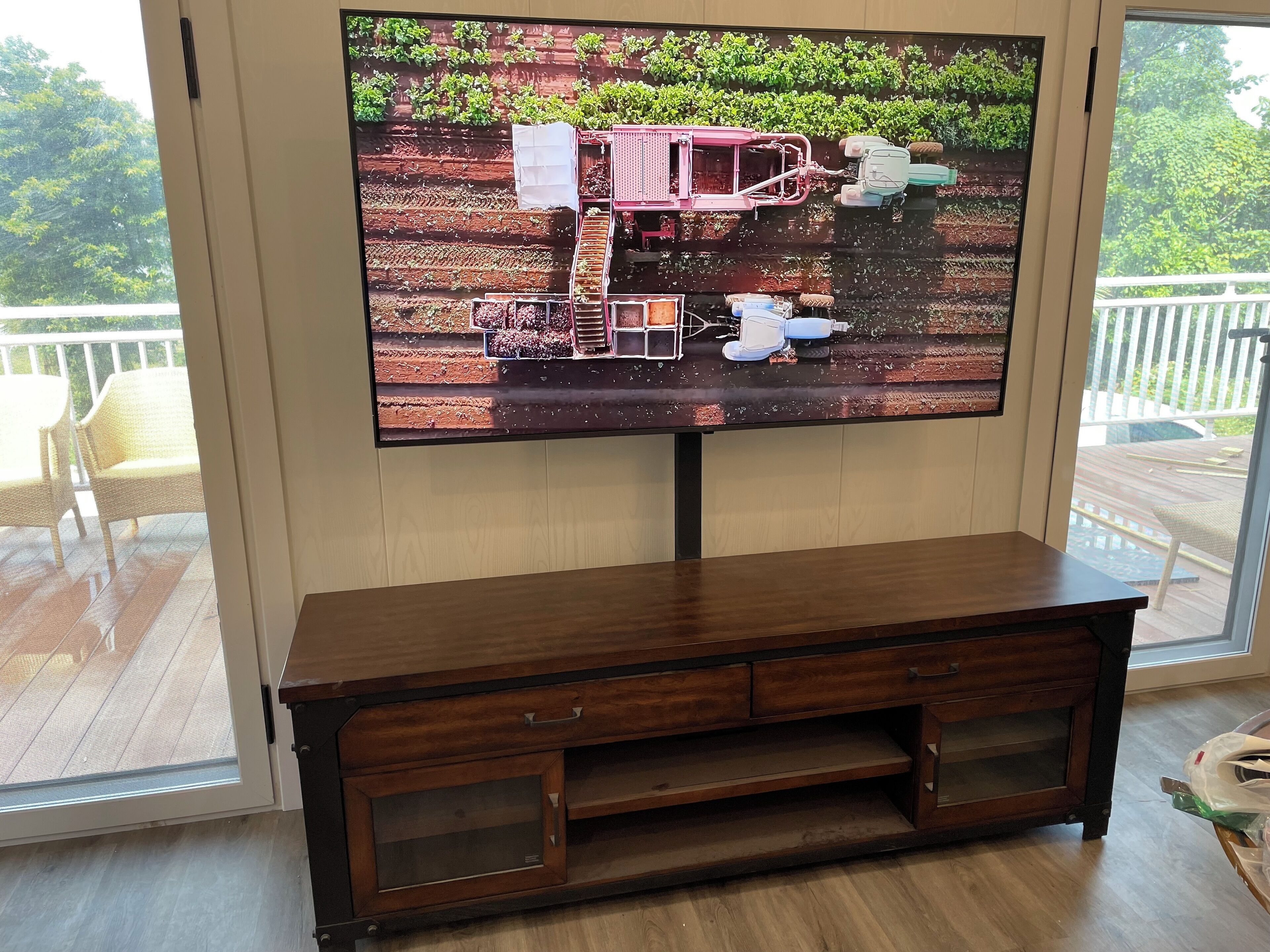 A television mounted on a wall with a wooden cabinet below.