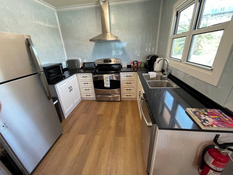 A modern kitchen with stainless steel appliances, white cabinetry, and a large window providing natural light.