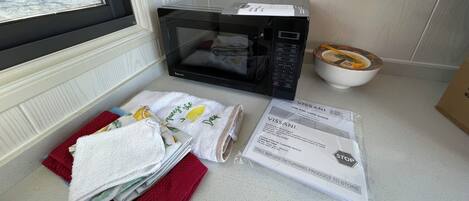 A kitchen with a microwave, a bowl, and a package of towels.