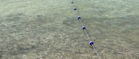 A clear view of a beach with a rope laid out across the water.