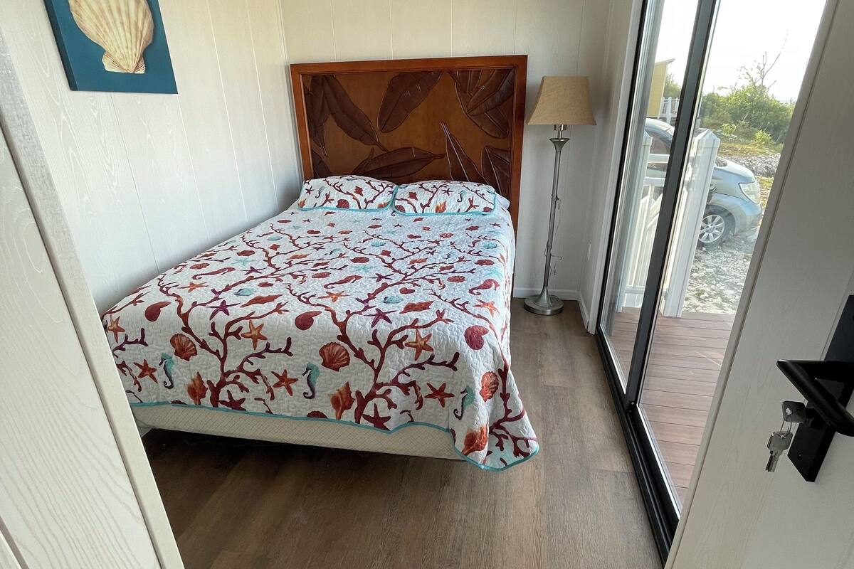 Une chambre à coucher avec un lit, un ventilateur de plafond, une fenêtre et une porte.