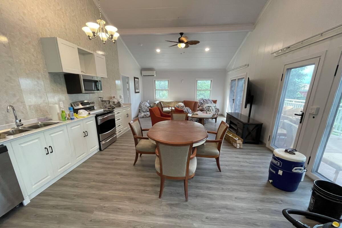 Une cuisine moderne avec des meubles blancs, une table à manger en bois et un ventilateur de plafond.