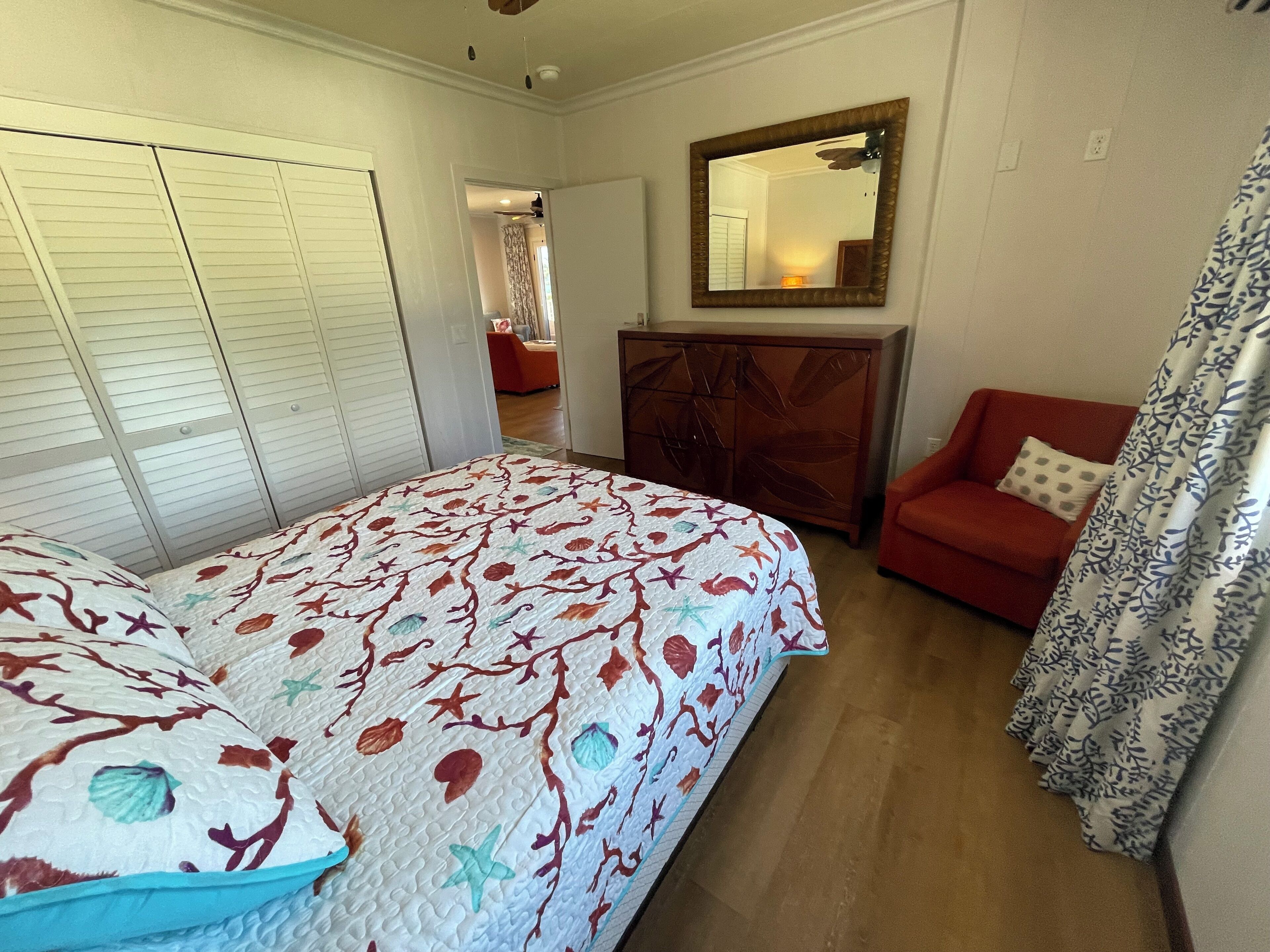 Una camera da letto con un letto, un divano rosso, un armadietto in legno e uno specchio a parete.