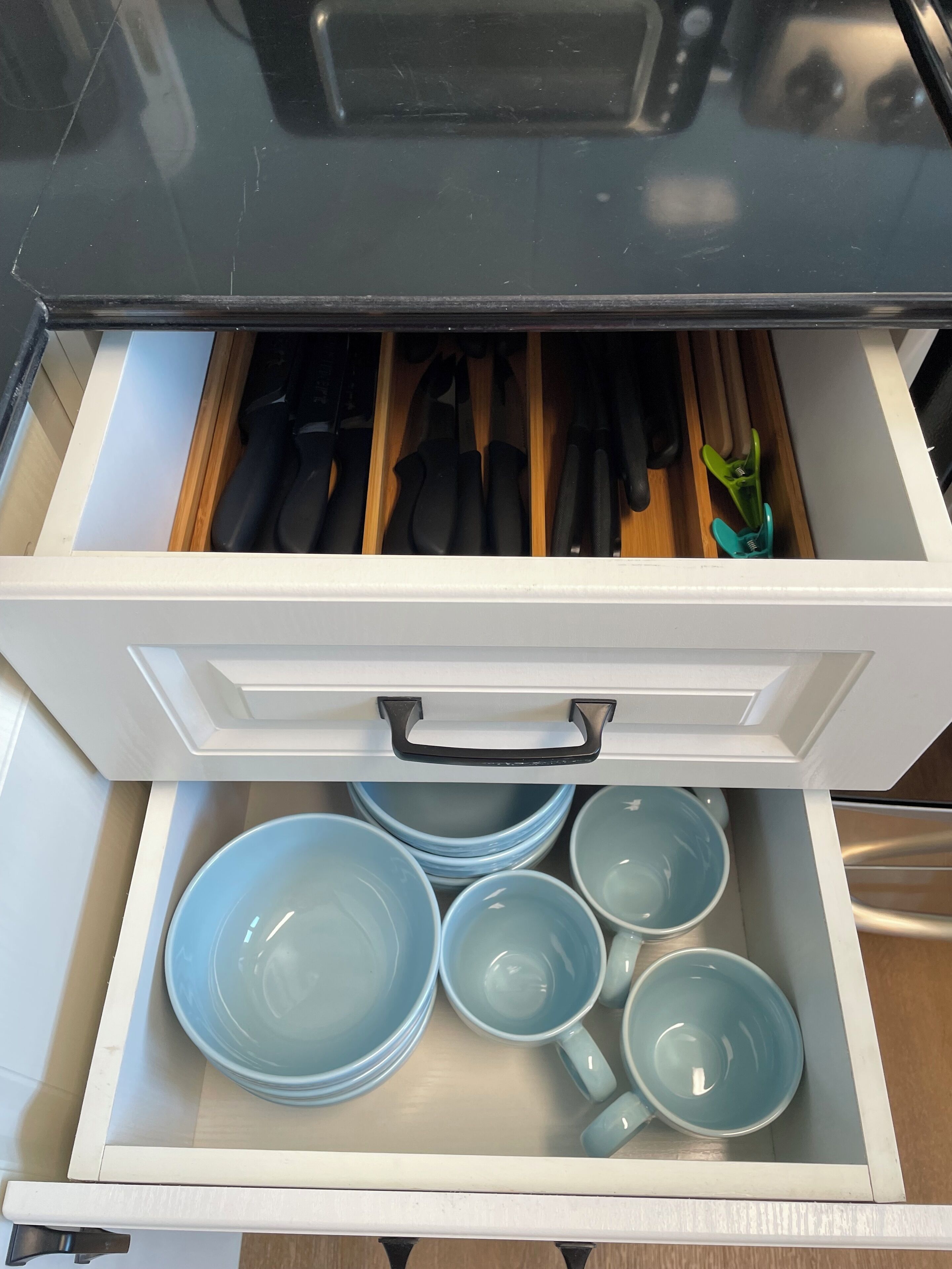 A drawer with kitchen utensils and blue ceramic dishes.