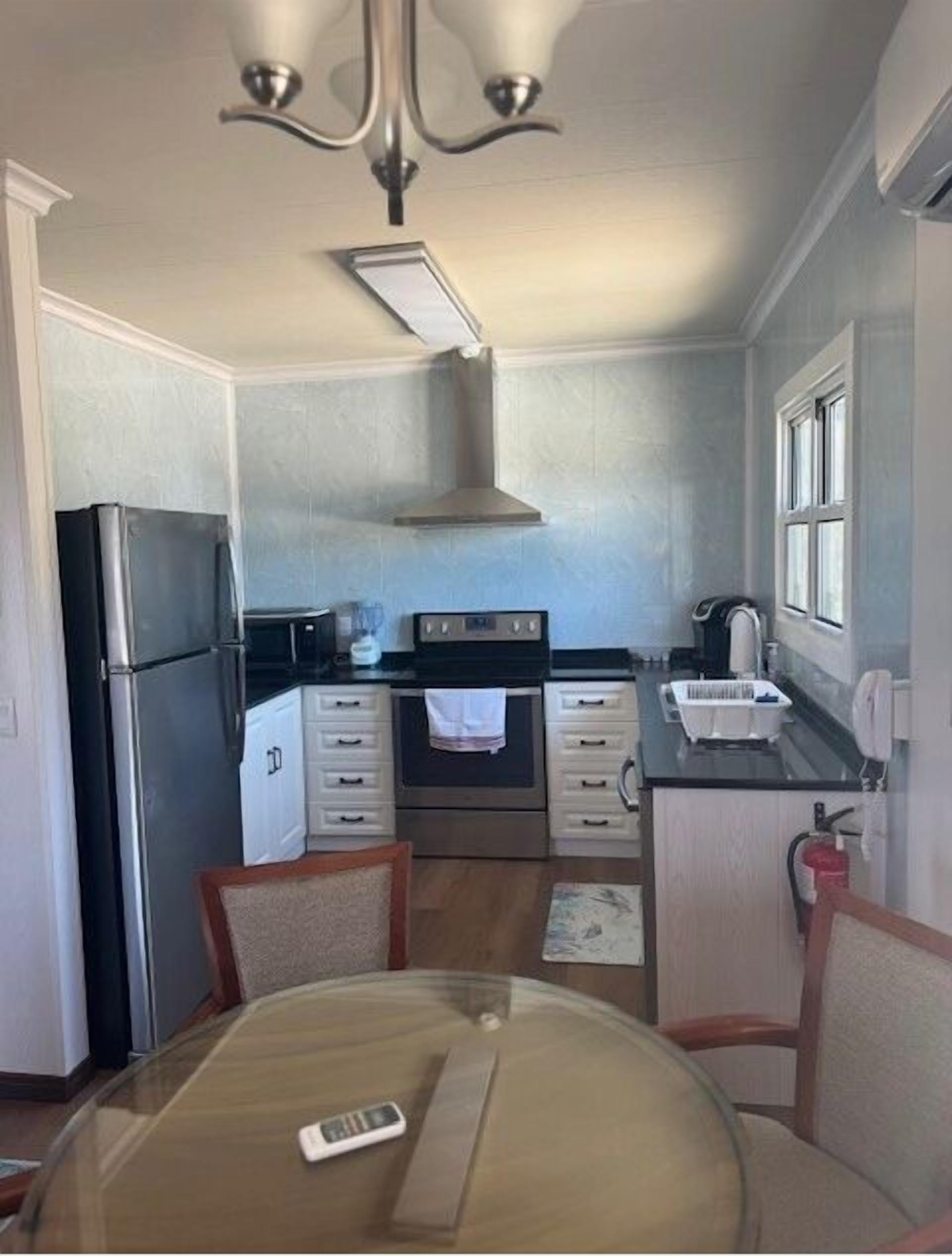 Une cuisine compacte équipée d’un réfrigérateur, d’un four et d’une petite table à manger avec des chaises.