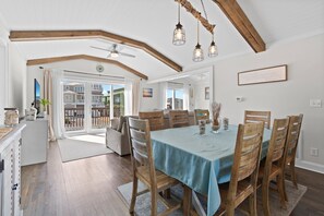 A dining area with a table set for six, wooden chairs, and a ceiling fan. - Ocean View, Private Heated Pool, 6BR, 4BA, Sleeps 14. Fall Getaway Package. (Holden Beach)