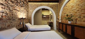 A room with two beds, a wooden cabinet, and a brick wall. - QUINTA SEIS TRES (Bogotá)