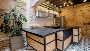Cozinha com bancada preta, armários de madeira e parede de tijolos.