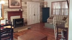 Ein gemütliches Wohnzimmer mit Kamin, einem Karo-Sofa und Holzboden.
