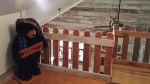 Eine Holztreppe mit einem 'WELCOME'-Schild, das von einem Teddybären gehalten wird.