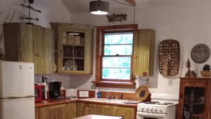 Eine Küche mit Holzschränken, einem weißen Kühlschrank, einem Herd und einem Fenster mit Blick auf Bäume.